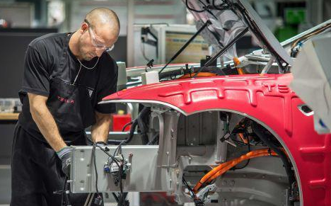 工人們?cè)谔厮估挥诩又莞ダ锩商氐墓S里組裝汽車(chē)